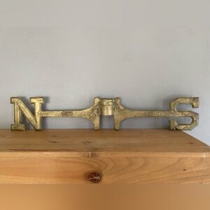Antique brass weathervane directional with North and South indicators.